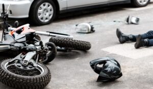 Legs of a person lying on the road after a motorcycle and car accident