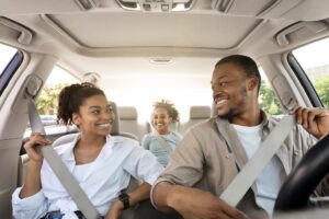 A family safely seated in a car, buckling up their seat belts, highlighting the need for seat belt replacement following a car accident.