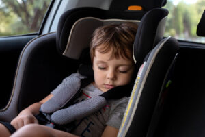 young boy sleeping in car seat in the backseat of vehicle