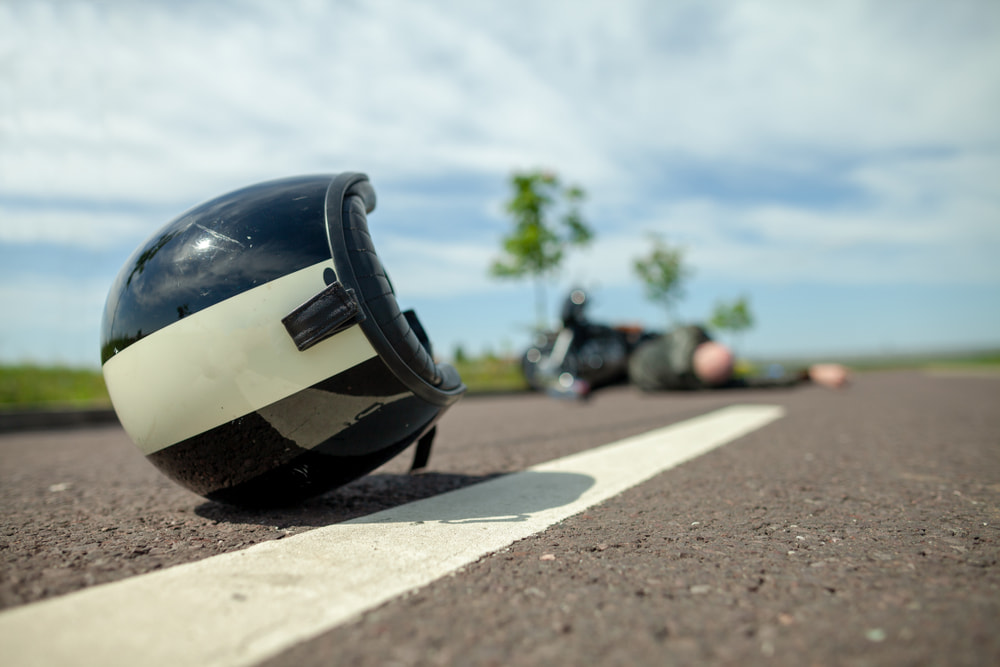 motorcycle helmet lying in the roadway with overturned motorcycle in the background